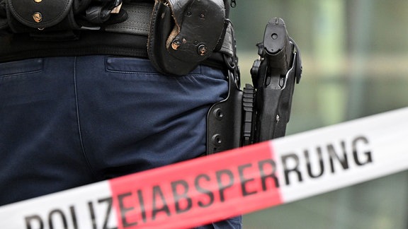 Bewaffneter Bundespolizist steht hinter Polizeiabsperrung