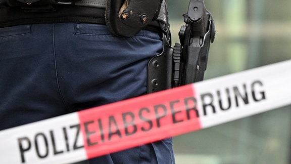 Bewaffneter Bundespolizist steht hinter Polizeiabsperrung