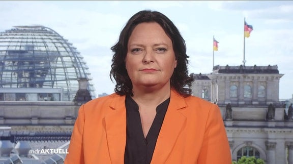 Eine Frau mit dunklen Haaren vor dem Panorama des Bundestags.