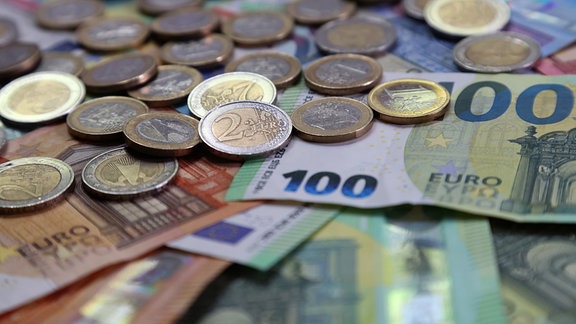 Verschiedene Euro-Banknoten und Euro-Münzen liegen auf einem Tisch.