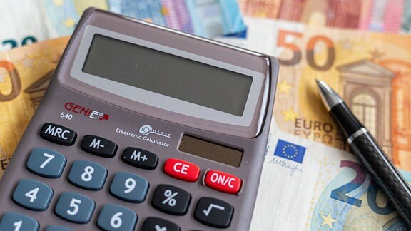 Ein Taschenrechner liegt auf Euro-Scheine.