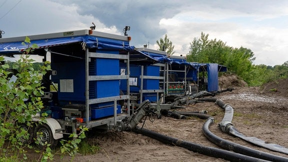 In einer schlammigen Landschaft stehen transportable Pumpstationen.