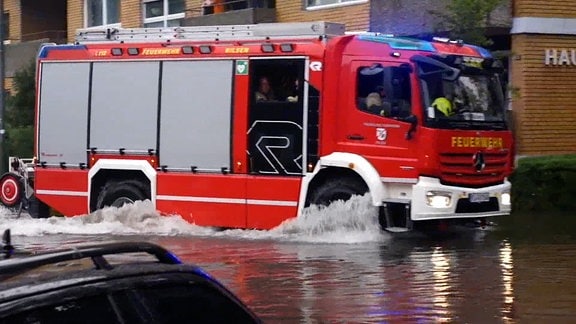 Ein Feuerwehr fährt über eine überflutete Straßen.