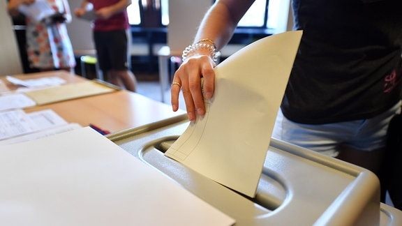 Eine Wählerin wirft den Stimmzettel in die Wahlurne bei der Stimmabgabe für die Landtagswahl in einem Wahllokal.