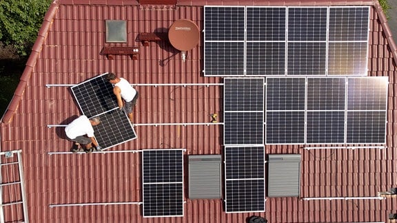 Eine Photovoltaikanlage wird auf dem Dach eines Einfamilienhauses installiert.