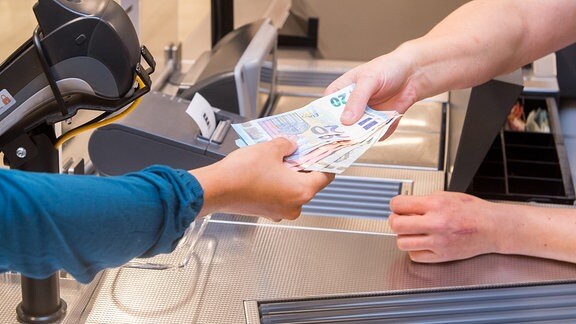 Eine Frau lässt sich 2018 an einer Kasse in einem Supermarkt Bargeld auszahlen.