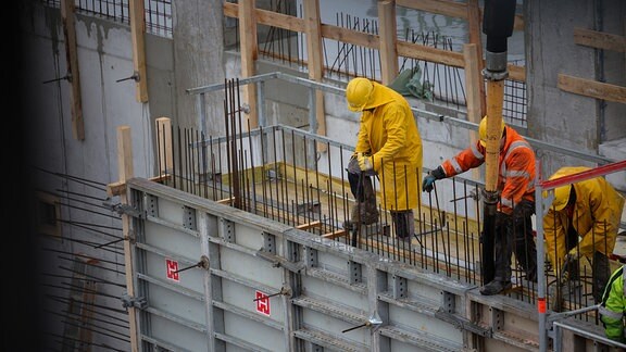 Arbeiter bei Betonarbeiten auf einer Baustelle für ein Industriegebäude.