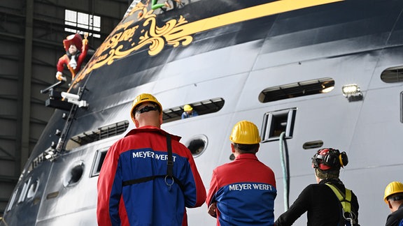 Mitarbeiter der Meyer Werft beobachten das Ausdocken des Kreuzfahrtschiffs „Disney Treasure“