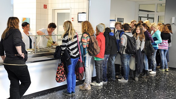Schüler stehen an der Essensausgabe einer Mensa 