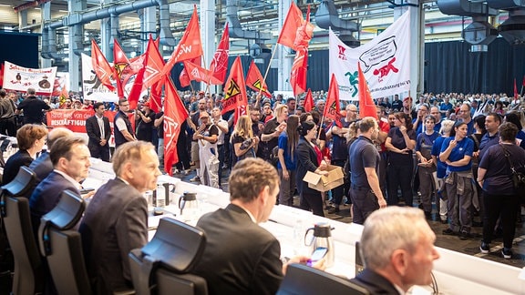 Mitarbeiter protestieren vor Beginn einer Betriebsversammlung in einer Halle im VW-Werk. 