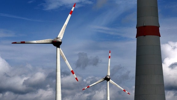 Windkraftanlagen sind vor einem bewölktem Himmel zu sehen. 