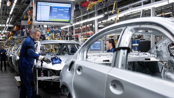 Mitarbeiter von BMW arbeiten im Stammwerk in der Produktion an der Karosserie von verschiedenen Modellen des Autoherstellers.