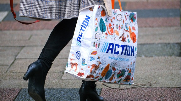 Eine Frau mit einer Einkaufstasche des Discounters Action