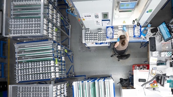 Eine Mitarbeiterin des Batteriezellenherstellers Skeleton Technologies GmbH sitzt in der Produktion von Superkondensatoren an einem Tisch.