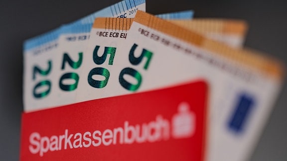 Geldscheine stecken in einem Sparbuch der Sparkasse