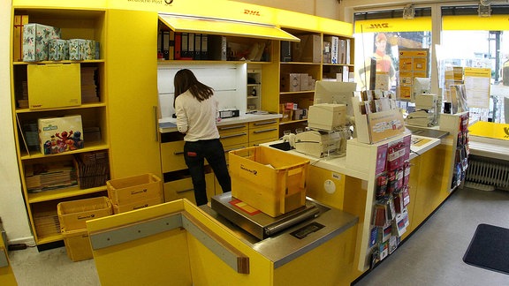 Ein Mitarbeiterin steht in einer Filiale der Deutschen Post