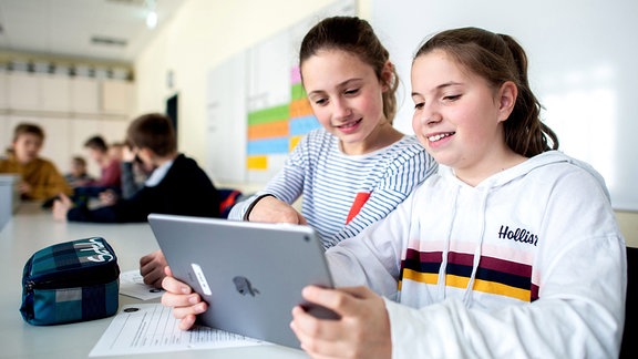 Schülerinnen lernen während des Unterrichts mit einem iPad