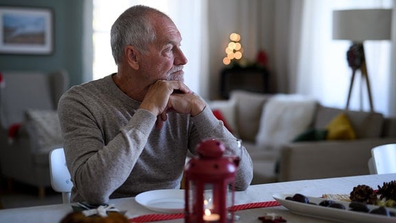 Ein älterer Mann sitzt allein am Tisch