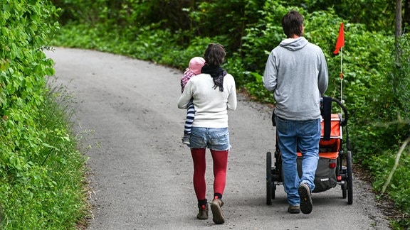 Ein Paar mit Kind läuft einen schmalen Weg entlang