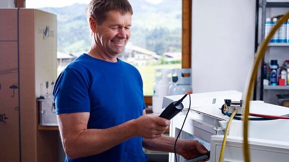 Ein Elektriker überprüft die Temperatur in einer Werkstatt