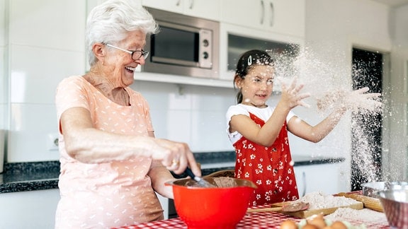 Kind hat neben Teig rührender Großmutter Spaß mit Mehl 