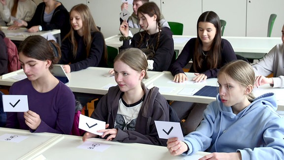 Schülerinnen mit Stimmkärtchen im Unterricht