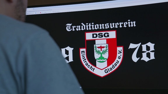 In weißer Schrift auf schwarzem Grund steht Traditionsverein DSG mit einem Wappen darunter auf einem Bildschirm.