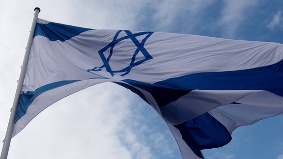 Die Fahne des Staates Israel weht vor blauem Himmel.