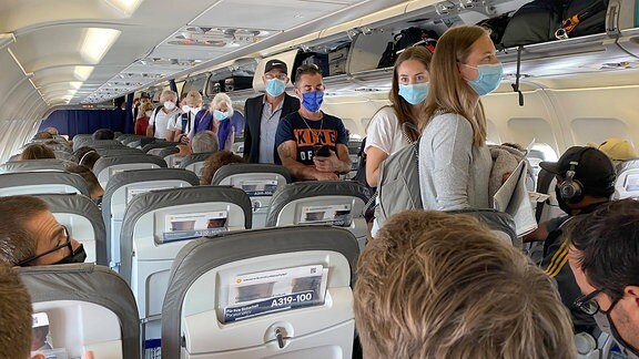 Passgiere mit Mundschutz in einem Flugzeug