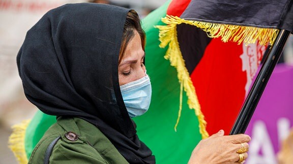 Eine Frau hält die Afghanische Fahne