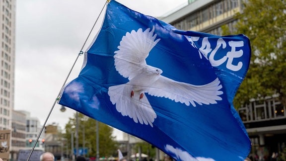 Fahne mit Friedenstaube bei der Demonstration "Die Waffen nieder" am Breitscheidplatz in Berlin.