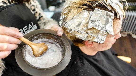 Die Haare eines Friseurkunden werden gefärbt