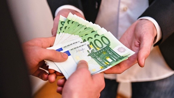 Mehrere 100-Euro-Banknoten werden übergeben