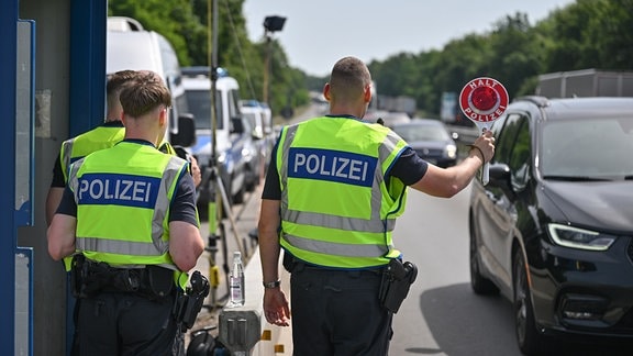 Beamte der Bundespolizei stehen an einer Autobahn nahe dem deutsch-polnischen Grenzübergang und stoppen ein Auto bei der Einreise nach Deutschland