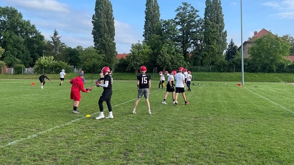 Mehrere junge Menschen trainieren American Football.