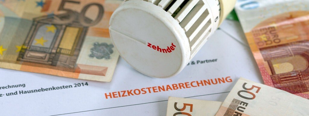 تصویر - یک ترموستات گرمایشی در بالای قبض گرمایش و اسکناس های یورو قرار دارد.