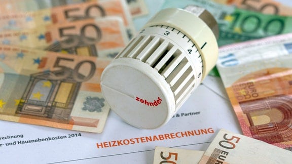 ILLUSTRATION - Ein Heizungsthermostat liegt auf der Heizkostenabrechnung und Euro-Geldscheinen.