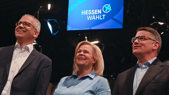 Die Spitzenkandidaten der hessischen Landtagswahl, Tarek Al-Wazir (Bündnis 90/Die Grünen, l-r), Wirtschaftsminister von Hessen, Nancy Faeser (SPD), Bundesinnenministerin, und Boris Rhein (CDU), Ministerpräsident von Hessen, stehen zu Beginn einer TV-Diskussionsrunde ("Triell") beim Hessischen Rundfunk (hr) zusammen.