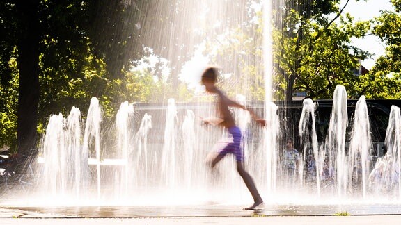 Ein Junge läuft durch einen Springbrunnen