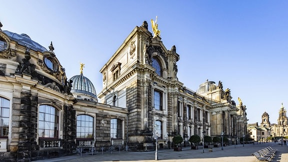 Blick auf die Hochschule für Bildende Künste Dresden: Ein graues Gebäude mit Kuppel, Skulpturen und Fassadenverzierungen.