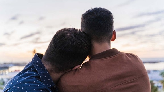 Symbolfoto eines schwulen Paares, dass sich den Sonnuntergang ansieht