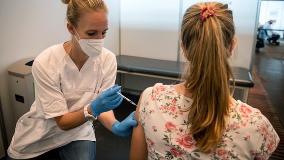 Eine junge Frau impft eine junge Patientin.
