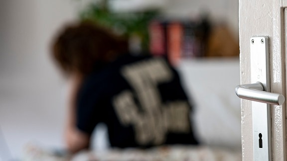 Eine Frau sitz im Bett in ihrer Wohnung.