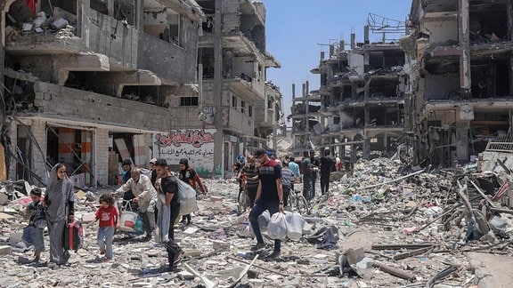 Palästinenser zwischen zerstörten Häusern in Jabalia