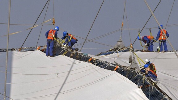 Das Khalifa International FIFA-Stadium westlich von Doha, im Aspire Park, ein Stadion der FIFA-Fussball-WM 2022. Dutzende Arbeiter, an Seilen gesichert, befestigen die Dachkonstruktion. 