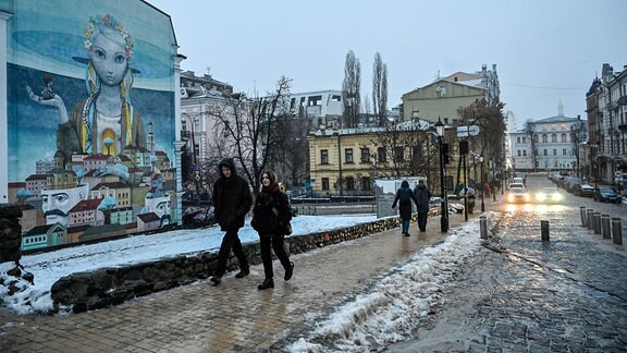 Menschen gehen während des Stromausfalls in Kiew die Straße entlang. 