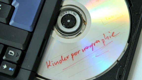 Eine DVD mit der Aufschrift 'Kinderpornographie' im Laufwerk eines Notebooks