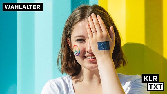 Eine junge Frau hält sich ein Auge mit der flachen Hand zu, auf ihren Handrücken ist die EU-Flagge geschminkt