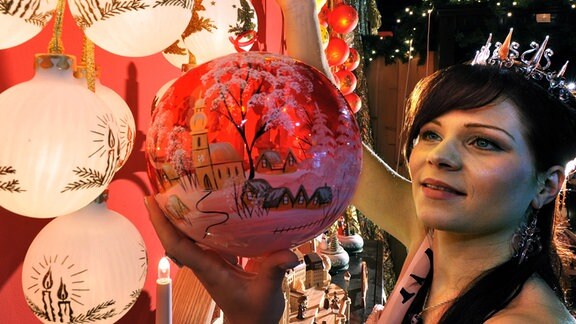 Festlich bemalte Christbaumkugeln betrachtet eine Frau in der Verkaufsausstellung der Farbglashütte im thüringischen Lauscha.