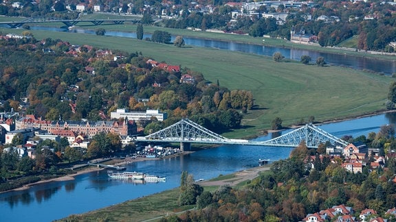 Ein historischer Schaufelraddampfer wendet auf der Elbe vor der Brücke Blaues Wunder.